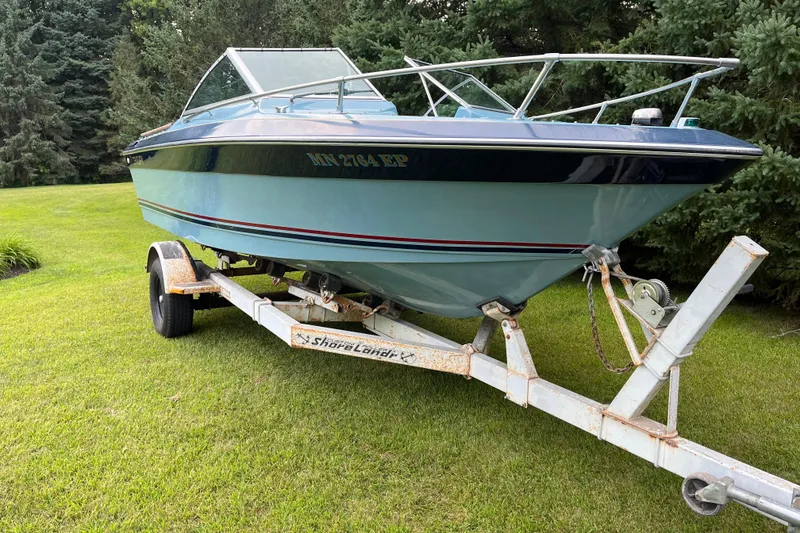 The Image of 1983 Century 3000 Bowrider boat on trailer, parked on grass with trees in background. - 0