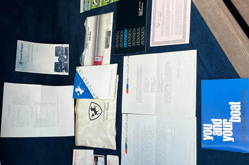 Slide: The Image of Assorted manuals and documents for a 1983 Century 3000 Bowrider boat on a blue surface. - 19