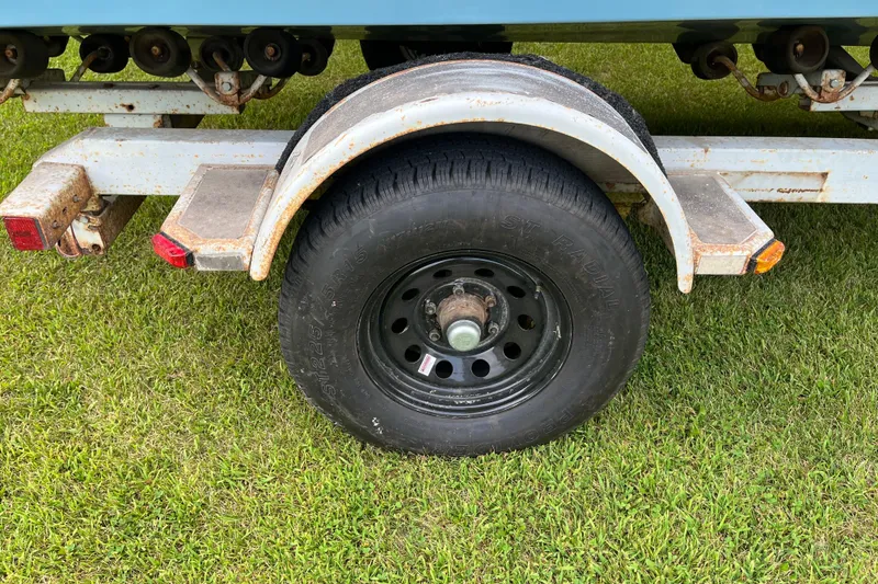 Slide: The Image of Trailer wheel of 1983 Century 3000 Bowrider on grass, showing rust and wear. - 28