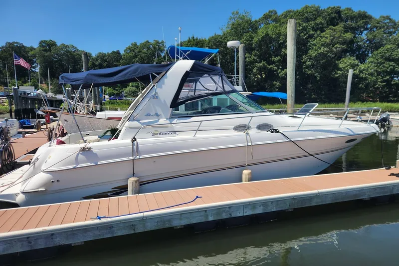 The Image of 1999 Sea Ray 310 Sundancer docked at a marina, featuring a sleek design and blue canopy. - 0