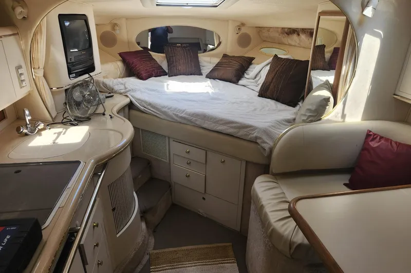Slide: The Image of 1999 Sea Ray 310 Sundancer cabin interior with bed, kitchenette, and seating area. - 15