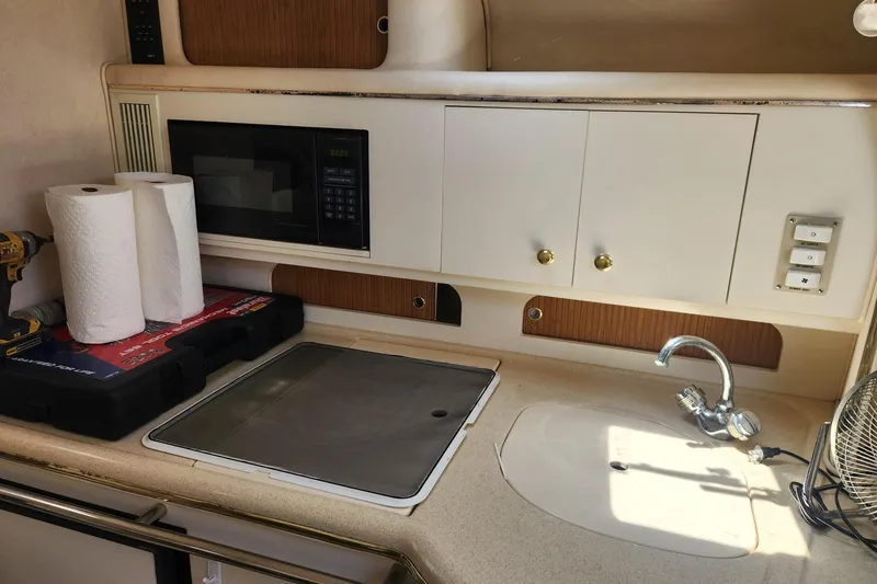 Slide: The Image of 1999 Sea Ray 310 Sundancer kitchen with microwave, sink, and storage cabinets. - 16