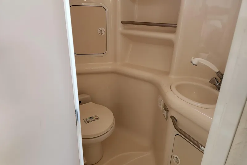 Slide: The Image of 1999 Sea Ray 310 Sundancer bathroom with toilet, sink, and storage compartments. - 19