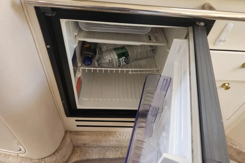 Slide: The Image of Open mini fridge on 1999 Sea Ray 310 Sundancer, containing water bottles and drinks. - 20