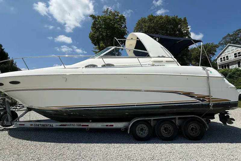Slide: The Image of 1999 Sea Ray 310 Sundancer boat on trailer, parked outdoors under a clear sky. - 21