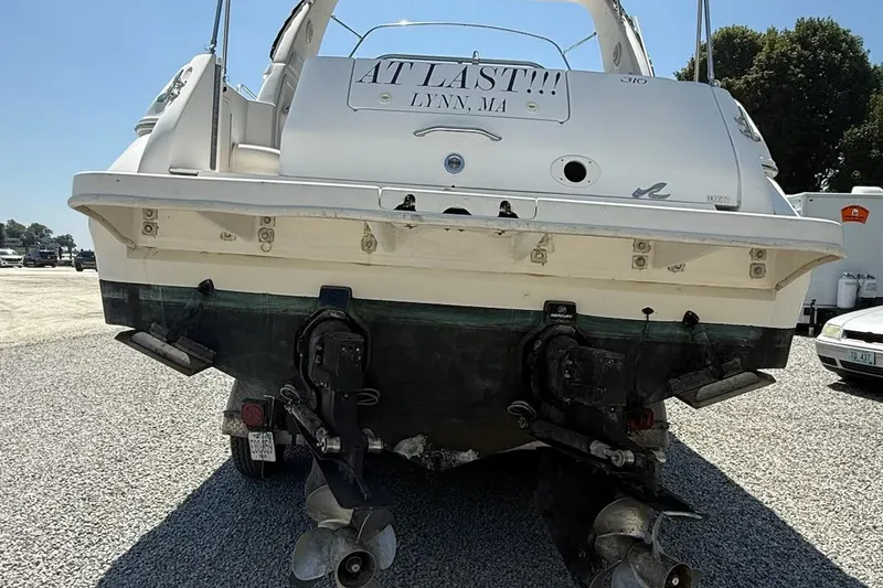 Slide: The Image of 1999 Sea Ray 310 Sundancer boat, rear view, on gravel lot. - 23