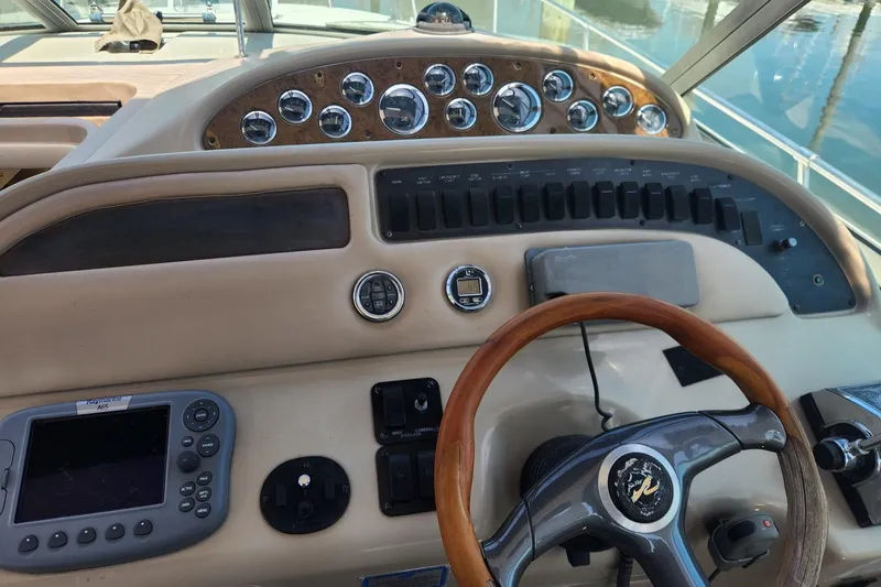 Slide: The Image of 1999 Sea Ray 310 Sundancer helm with gauges, controls, and wooden steering wheel. - 9
