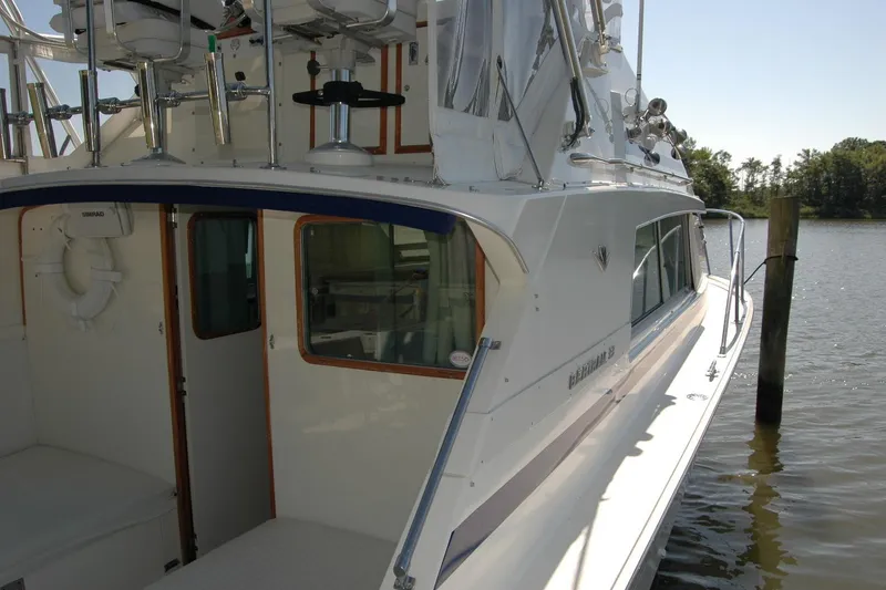 Slide: The Image of 1987 Bertram 33 Sport Fisherman boat docked by the water, showcasing its sleek design. - 23