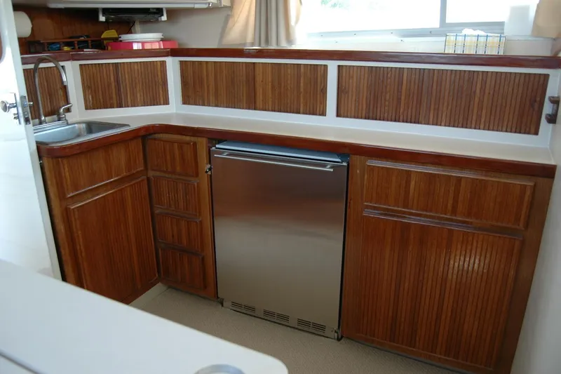 Slide: The Image of 1987 Bertram 33 Sport Fisherman galley with wood cabinetry and stainless steel fridge. - 74