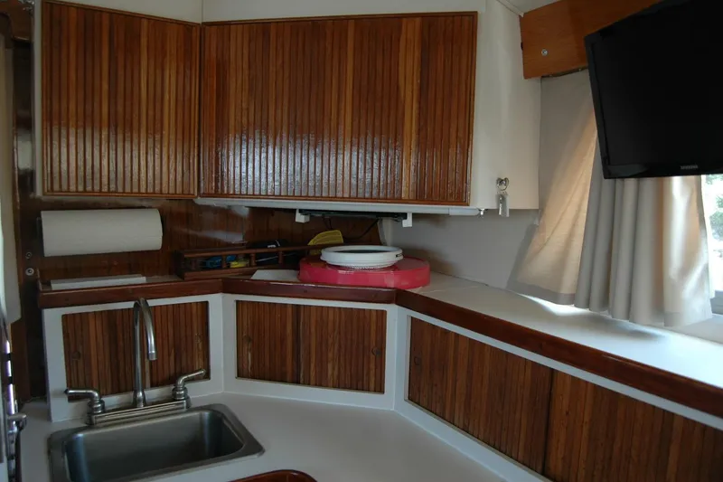 Slide: The Image of 1987 Bertram 33 Sport Fisherman interior kitchen with wooden cabinets and modern amenities. - 75