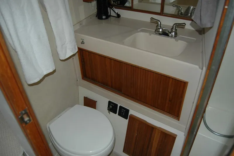 Slide: The Image of 1987 Bertram 33 Sport Fisherman bathroom with sink, toilet, and wooden cabinetry. - 80