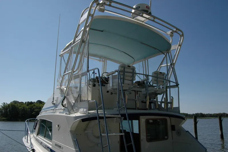 Slide: The Image of 1987 Bertram 33 Sport Fisherman boat with elevated helm, docked on a sunny day. - 9