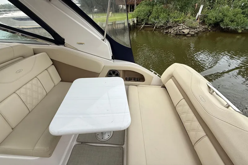 Slide: The Image of 2020 Regal 28 Express boat interior with beige seating and a white table by the water. - 10
