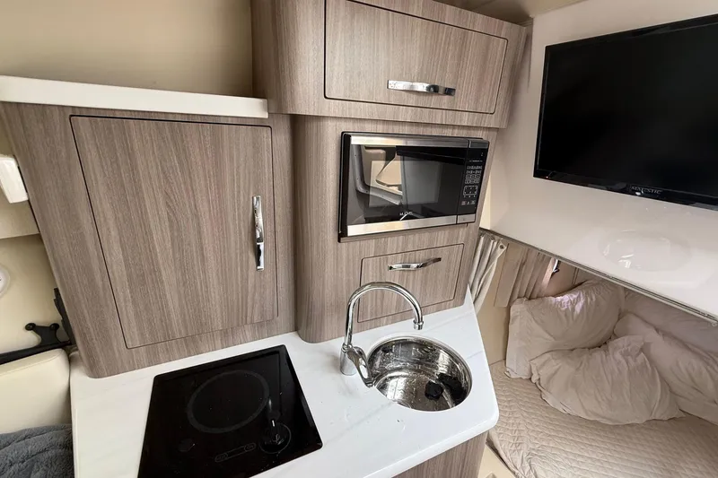 Slide: The Image of 2020 Regal 28 Express boat interior with kitchenette, microwave, sink, and TV. - 24