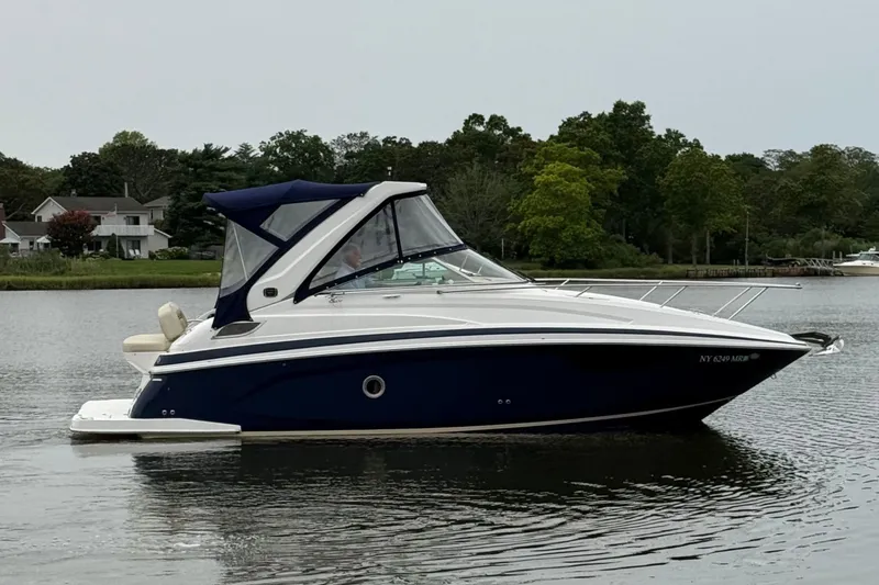 Slide: The Image of 2020 Regal 28 Express boat on calm water near shoreline with trees and houses. - 4