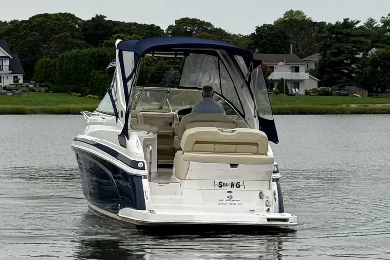 Slide: The Image of 2020 Regal 28 Express boat cruising on a calm lake near residential area. - 6