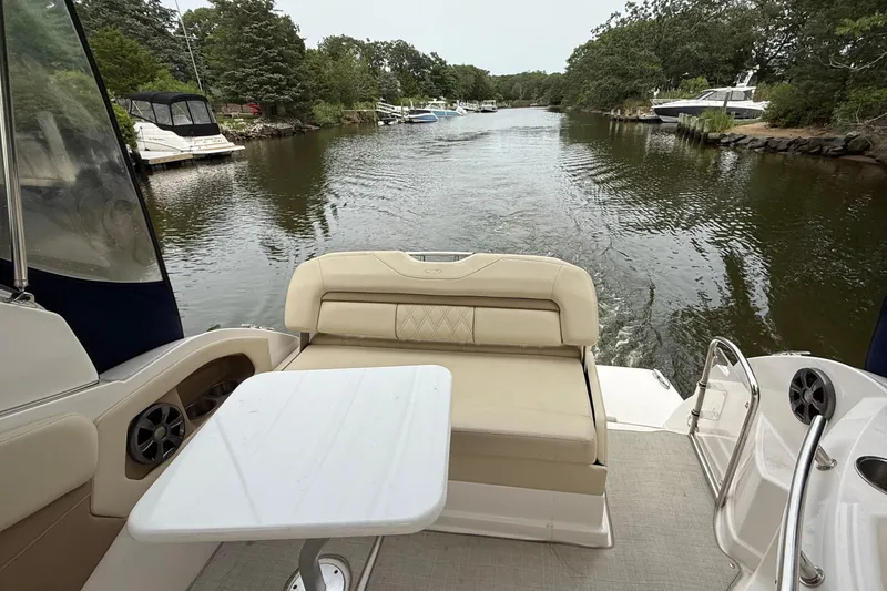 Slide: The Image of 2020 Regal 28 Express boat interior with seating and table on a scenic waterway. - 9