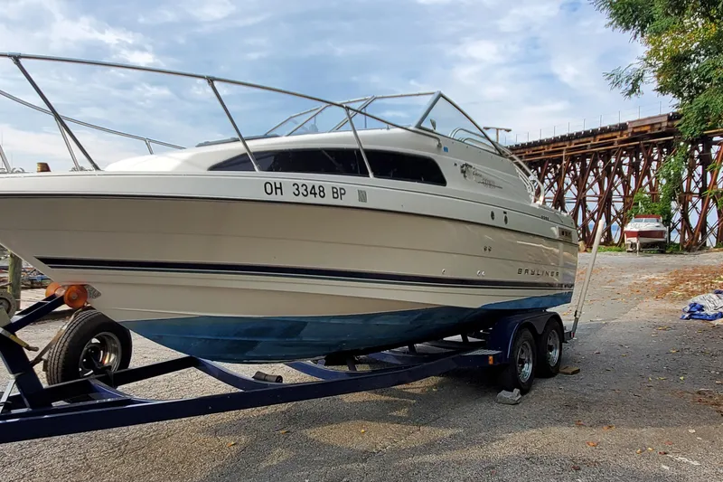 Slide: The Image of 1996 Bayliner 2252 Ciera Express boat on trailer, parked near a bridge. - 3