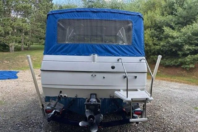 Slide: The Image of 1996 Bayliner 2252 Ciera Express boat with blue canopy, parked on gravel near trees. - 39