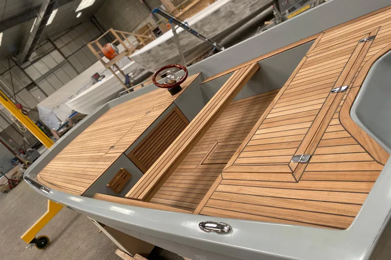 Slide: The Image of 2026 Black Pepper Tender 17 boat with sleek wooden deck in a workshop setting. - 6