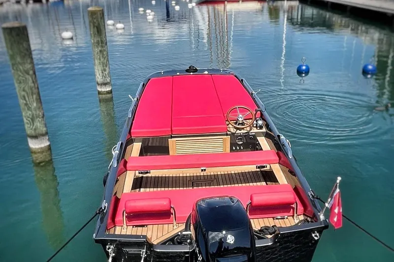 Slide: The Image of Luxury Black Pepper Tender 17 boat with red seating, docked in a serene marina. - 3