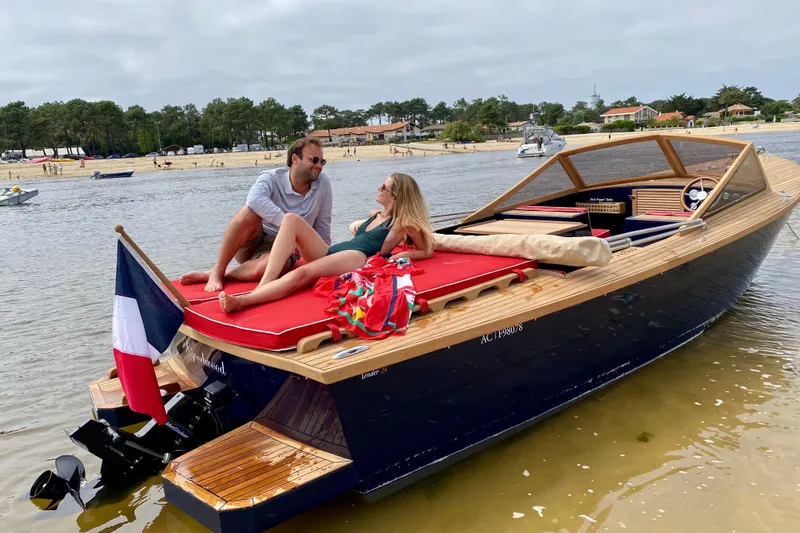 Slide: The Image of Couple relaxing on Black Pepper Tender 24 boat, 2026 model, near a scenic beach. - 13