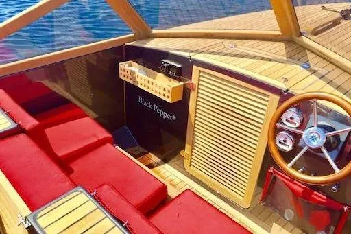 Slide: The Image of Luxurious Black Pepper Tender 24 boat interior with red seating and wooden steering wheel, 2026 model. - 5