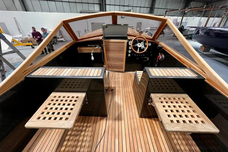 Slide: The Image of Interior of Black Pepper Tender 24 boat, showcasing wooden deck and steering wheel, 2026 model. - 11