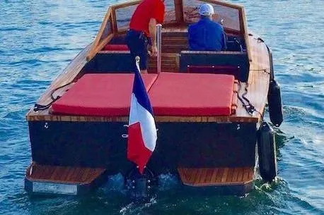 Slide: The Image of Black Pepper Tender 24 boat cruising on water, featuring red seating and a French flag. - 7