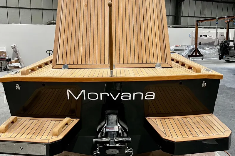 Slide: The Image of 2026 Black Pepper Tender 24 boat with wooden deck, named "Morvana," in a warehouse setting. - 9