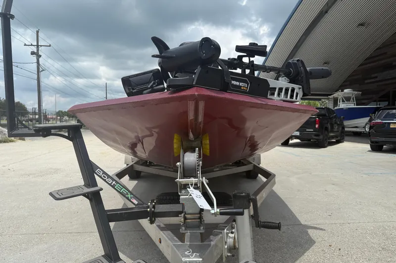 Slide: The Image of 2021 SeaArk BC 210 boat on trailer, equipped with Minn Kota motor, parked outdoors. - 2
