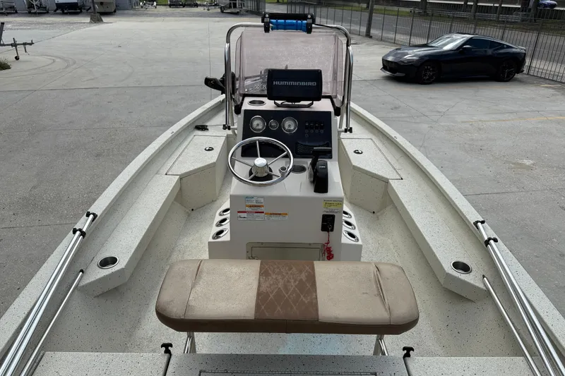 Slide: The Image of 2020 Xpress H20B boat interior with steering console and seating, parked on concrete. - 7