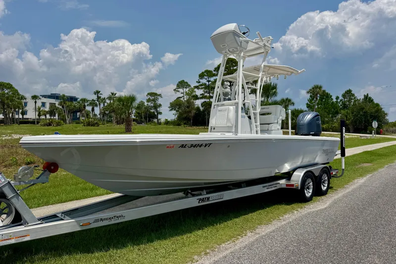 Slide: The Image of 2023 Pathfinder 2500 Hybrid boat on trailer, parked roadside under a cloudy sky. - 1