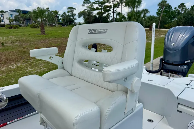 Slide: The Image of 2023 Pathfinder 2500 Hybrid boat seat with armrests, outdoor setting, lush greenery background. - 11