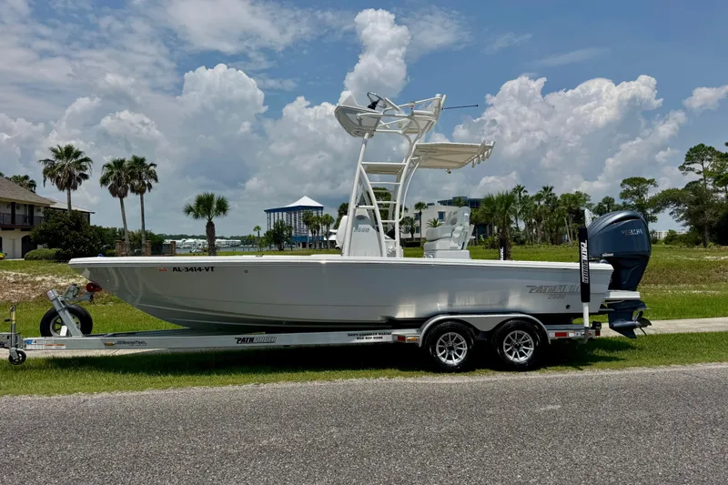 Slide: The Image of 2023 Pathfinder 2500 Hybrid boat on trailer, parked outdoors under a cloudy sky. - 2