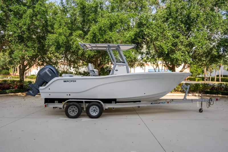 Slide: The Image of 2025 Sea Fox 228 Commander boat on trailer, parked outdoors with trees in background. - 7