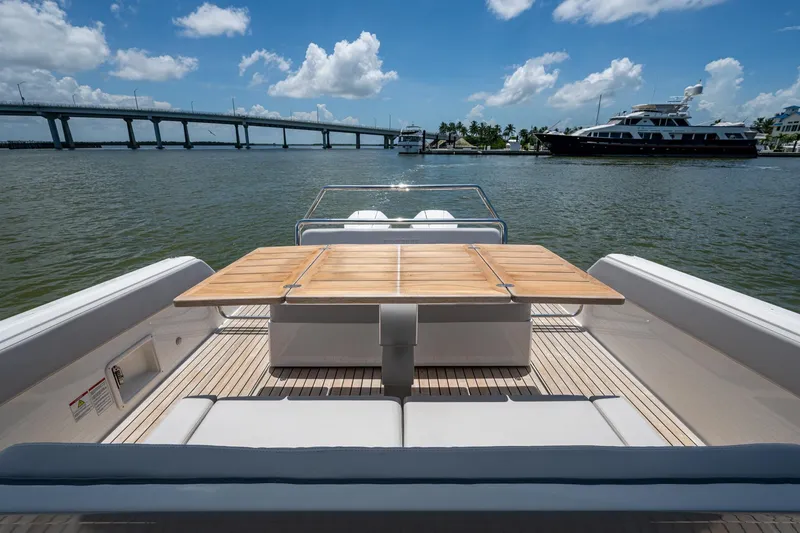 Slide: The Image of 2023 Schaefer V33 yacht with wooden deck and table, near a bridge and marina. - 16