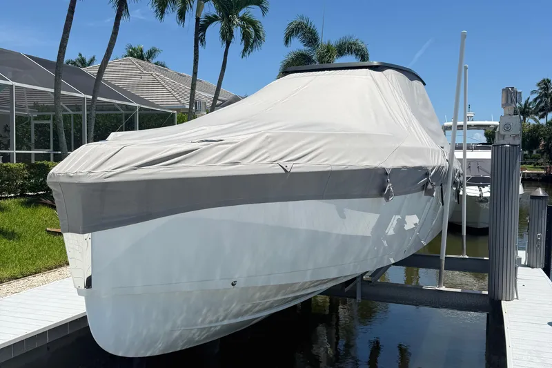 Slide: The Image of 2023 Schaefer V33 boat covered and docked, surrounded by tropical palm trees. - 49
