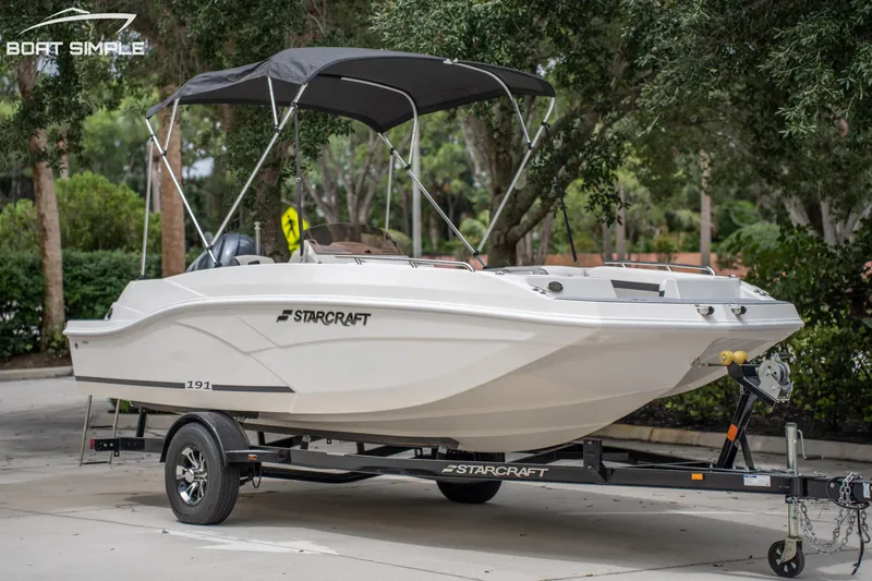 Slide: The Image of 2024 Starcraft SVX 191 OB boat on trailer with canopy, parked outdoors. - 6