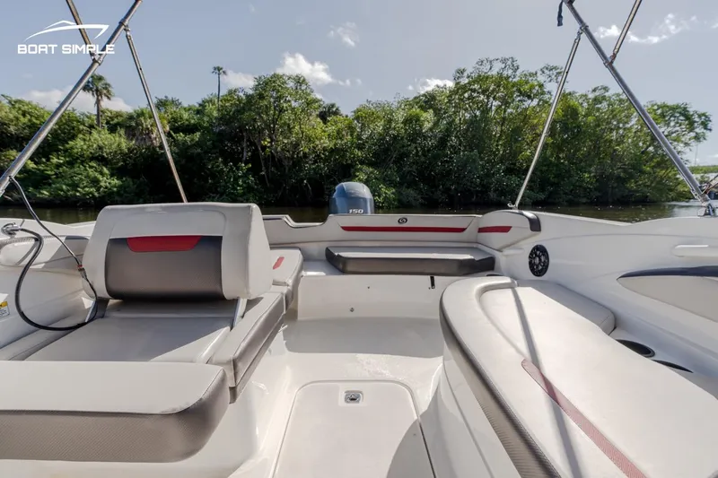 Slide: The Image of 2023 Hurricane SunDeck Sport 205 OB boat interior with seating and lush greenery backdrop. - 7