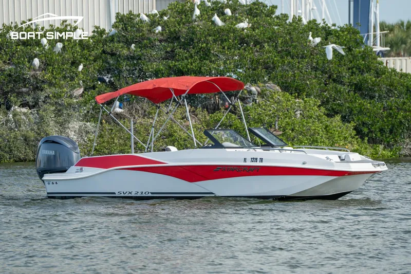 Slide: The Image of 2024 Starcraft SVX 210 OB DC boat with red canopy on water. - 1