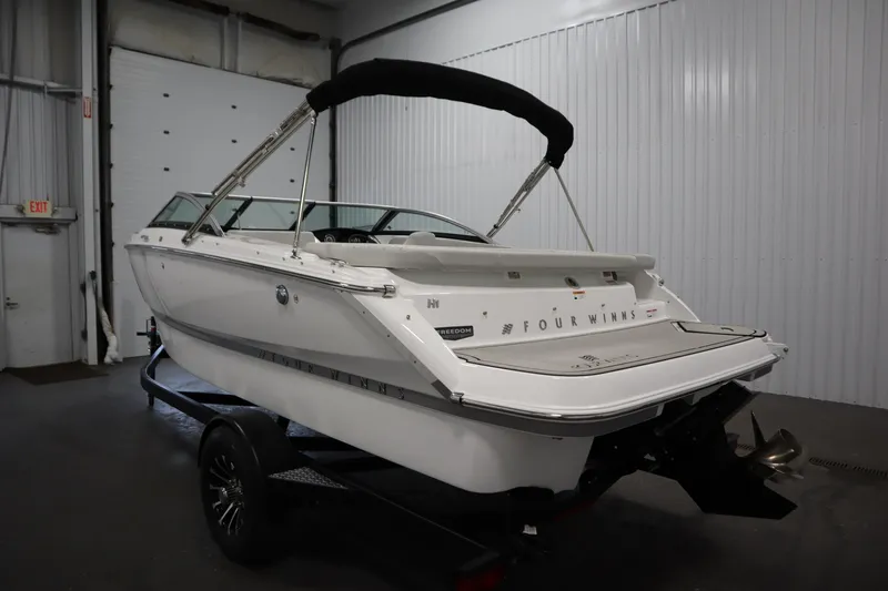 Slide: The Image of 2026 Four Winns H1 Freedom boat in a garage, rear view on trailer. - 10