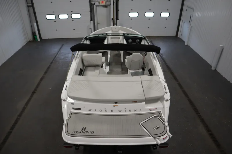 Slide: The Image of 2026 Four Winns H1 Freedom boat in a garage, rear view showcasing interior seating. - 13