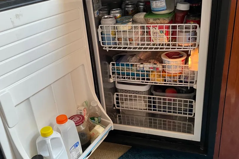 Slide: The Image of Open refrigerator on 2004 Sea Ray 420 Sundancer, stocked with various food and drinks. - 26