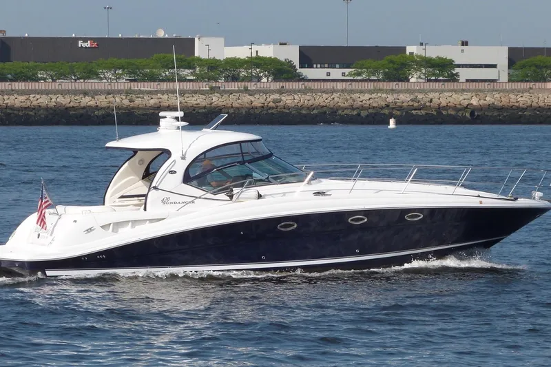 Slide: The Image of 2004 Sea Ray 420 Sundancer yacht cruising on water near industrial buildings. - 6