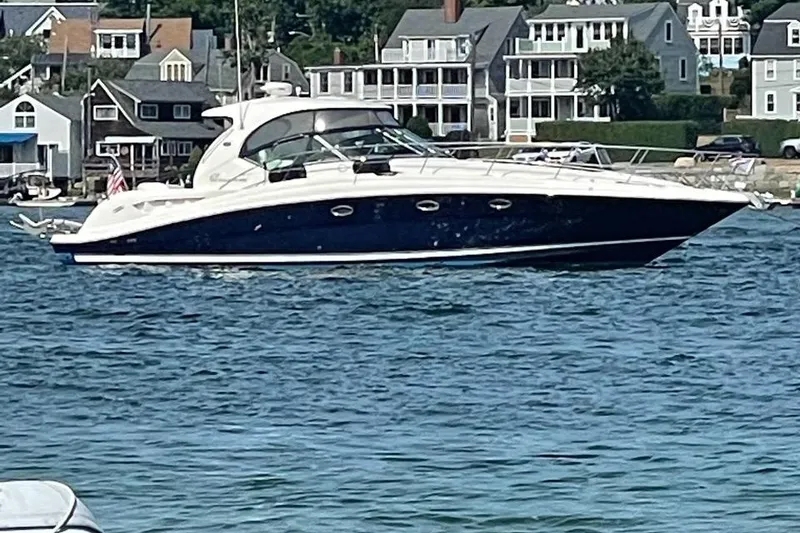 Slide: The Image of 2004 Sea Ray 420 Sundancer yacht cruising near coastal homes. - 8