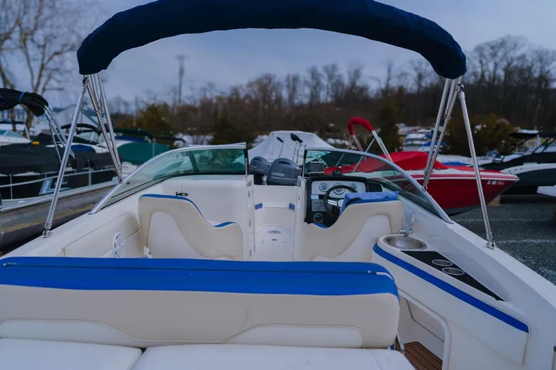 Slide: The Image of 2013 Sea Ray 240 Sundancer boat interior with blue and white seating, docked outdoors. - 9