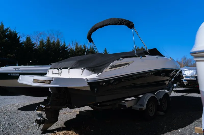 Slide: The Image of 2012 Sea Ray 240 Sundeck boat on trailer, covered, under clear blue sky. - 2