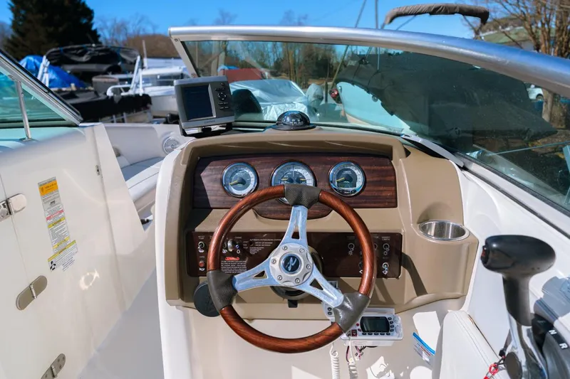 Slide: The Image of 2012 Sea Ray 240 Sundeck dashboard with steering wheel and gauges in a sunny marina. - 4