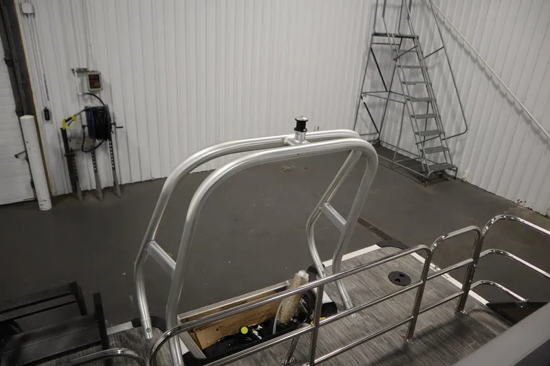 Slide: The Image of 2026 Bentley Pontoons Legacy 223 Swingback Tri-toon interior with metal railings in a warehouse. - 30